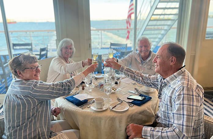 Four passengers at a dining table, raising their wine glasses to toast each other