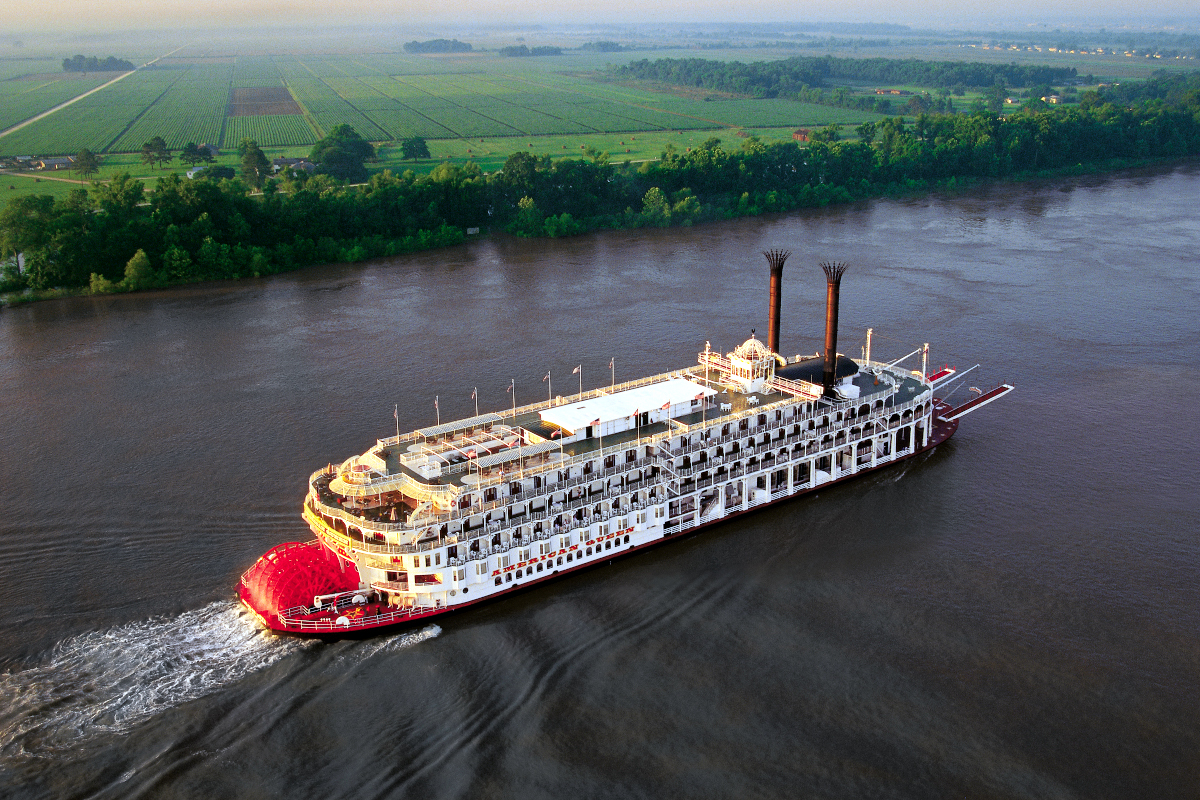 Aerial view of the American Queen sailing a river along farmland