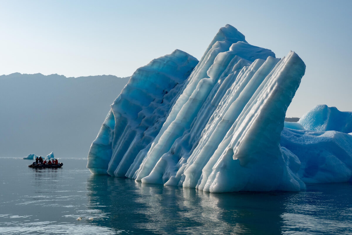 Alaska glacier iceberg with a zodiac of guests exploring