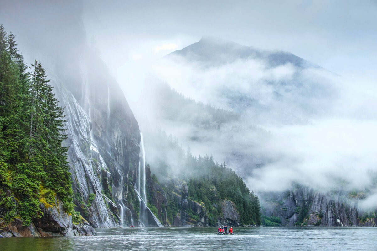Zodiacs filled with guests in Misty Fjords approaching some waterfalls