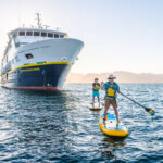 Two guests paddleboarding from the National Geographic Venture in the waters of the Sea of Cortez