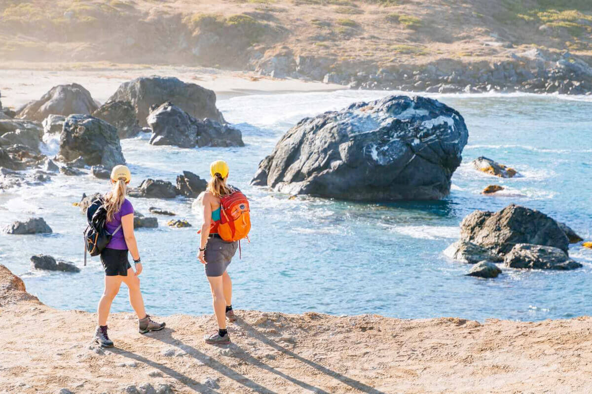A couple of cruise guests on top of a cliff overlooking a rocky beach