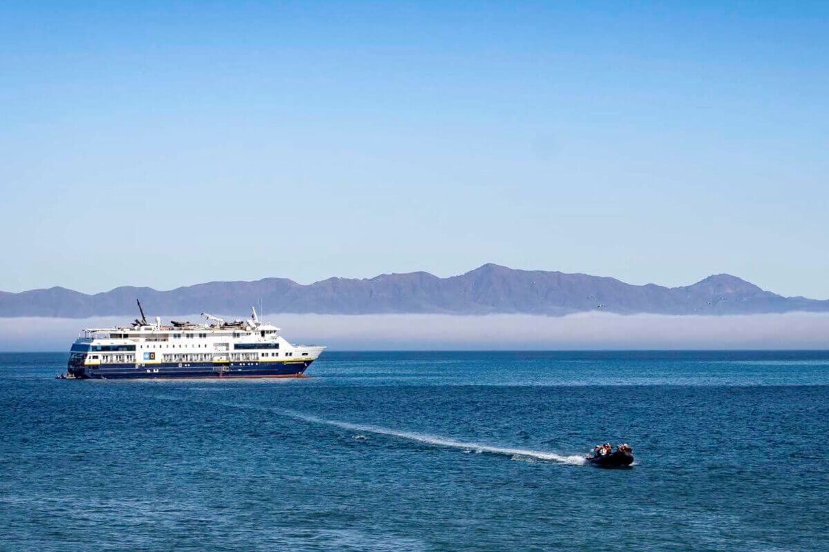 Zodiac filled with cruise guests sailing away from the National Geographic Venture to explore the Baja coast