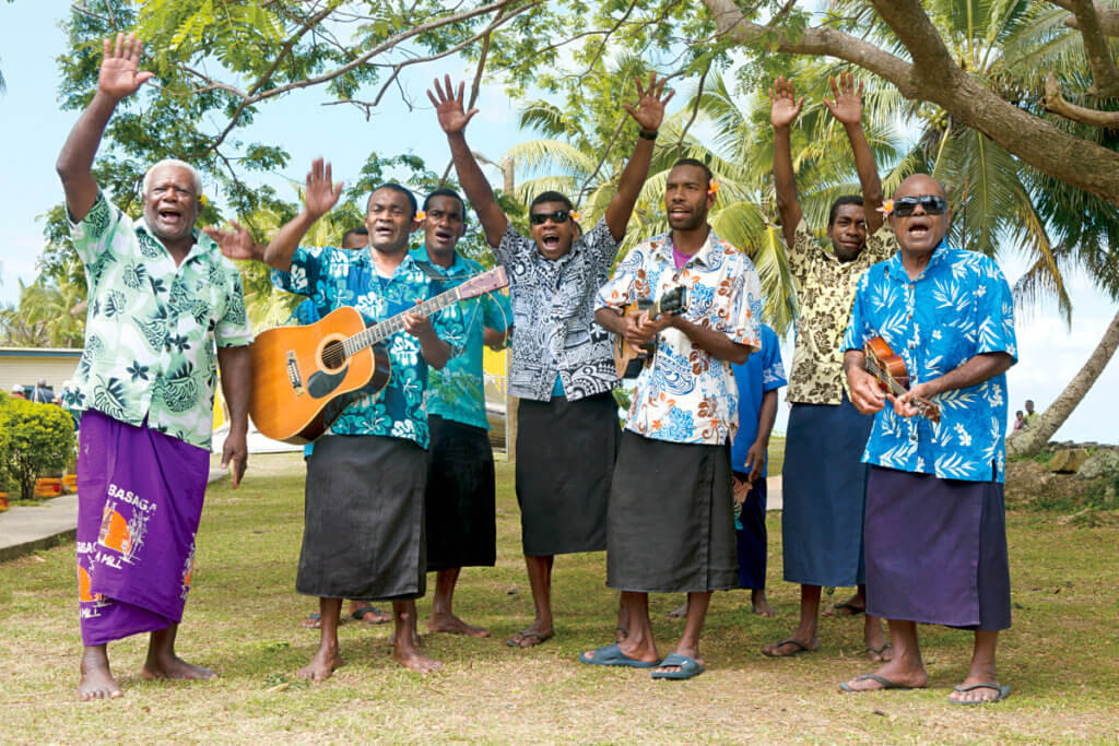 A male group of musicians performing under some trees in Fiji