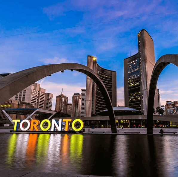 Toronto City Hall Pool with a lighted Toronto sign at dusk