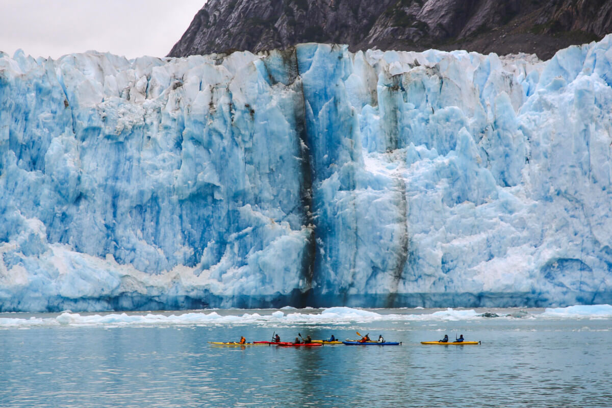 Glacier Bay, with a group of kayakers exploring at the face of a huge glacier