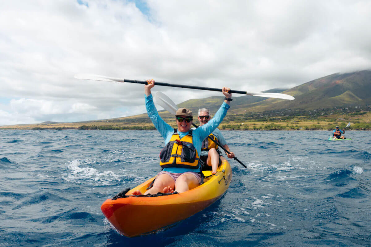 A couple in a yellow open sea kayak off the coast of Hawaii