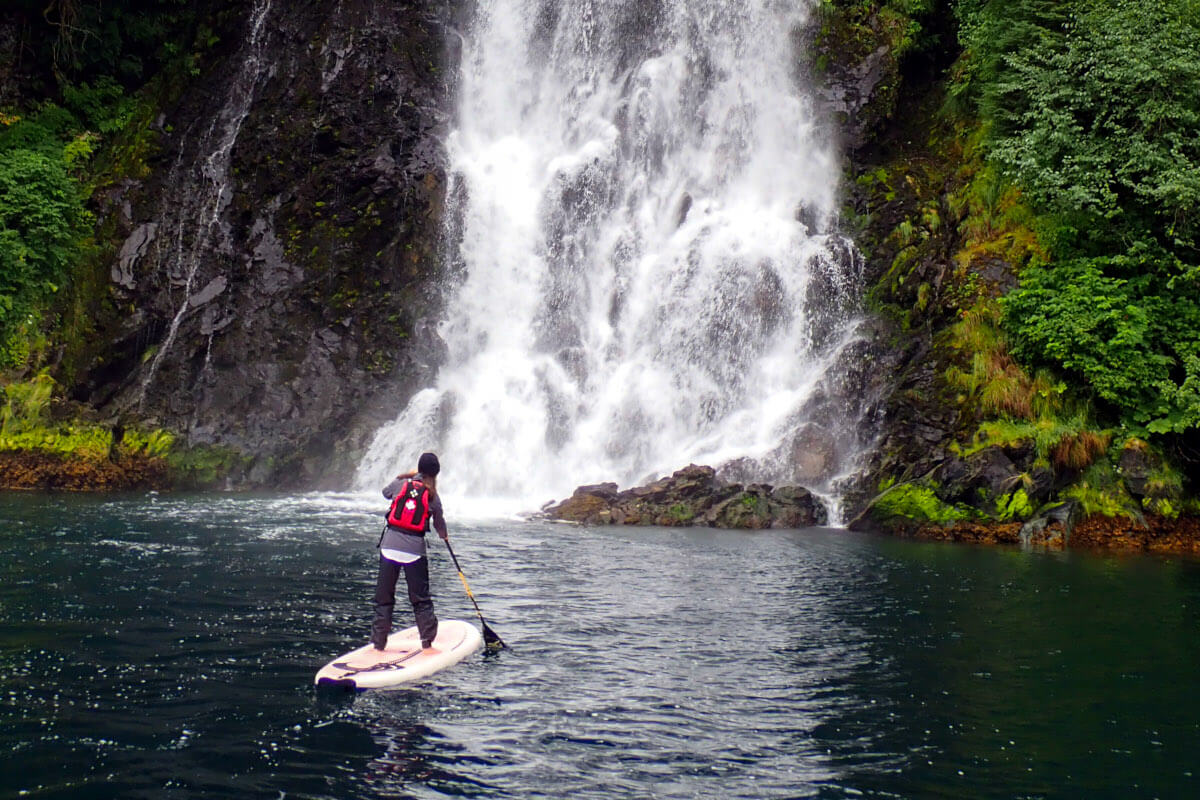 Paddleboarding in front of waterfall