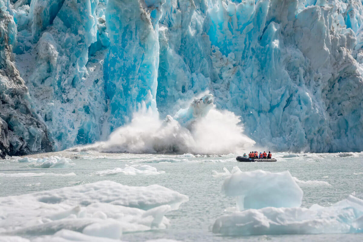 A zodiac filled with cruise guests experiencing a calving glacier